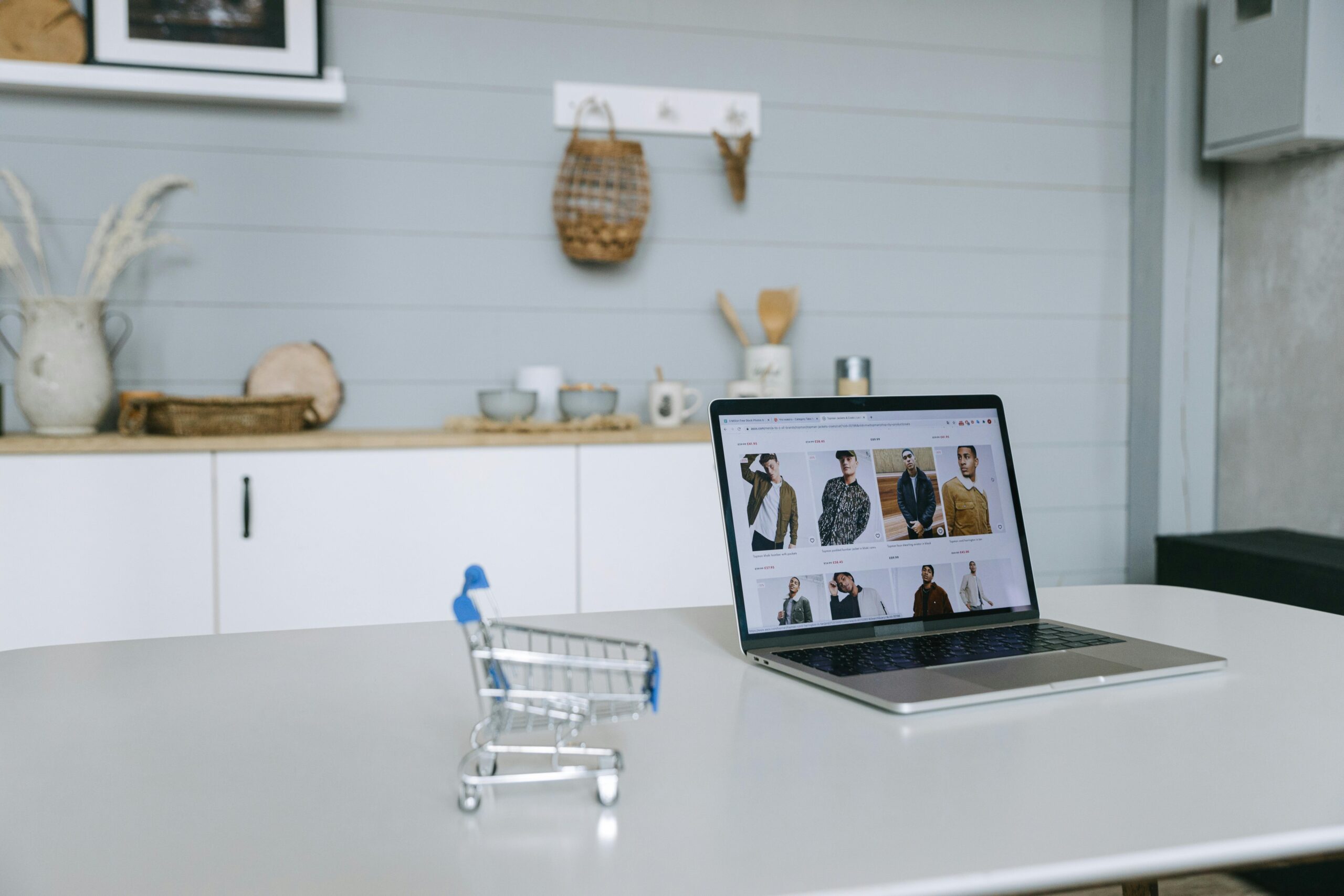 A laptop displaying an online clothing store next to a small shopping cart — representing ecommerce platform decisions for South African businesses